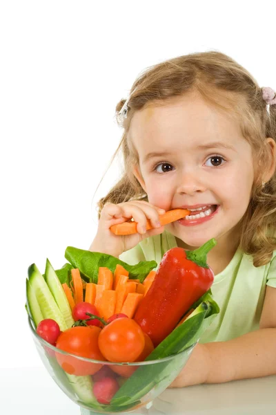 Маленькая девочка пробует и жует морковку — стоковое фото