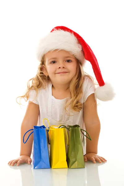 Kleines Mädchen mit Weihnachtsmütze und Einkaufstaschen — Stockfoto