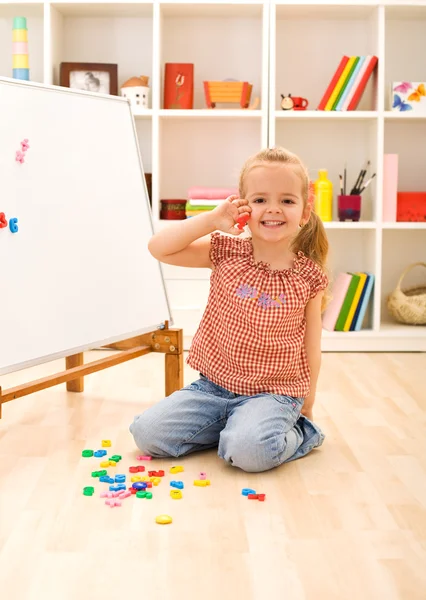 Счастливая маленькая девочка изучает цифры — стоковое фото