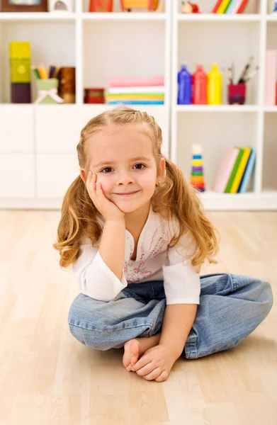 Счастливая маленькая девочка сидит в своей комнате дома — стоковое фото