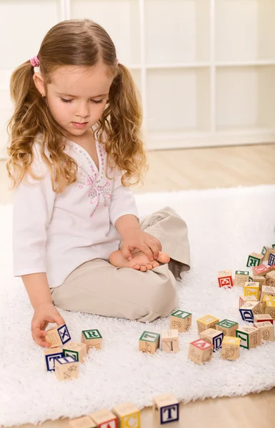 Malá dívka si hraje s dřevěnými bloky — Stock fotografie