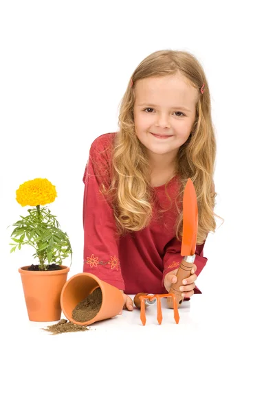 Liten flicka med trädgårdsredskap och krukväxt blomma — Stockfoto