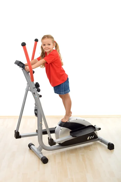 Little girl standing on top of elliptical trainer — Stock Photo, Image