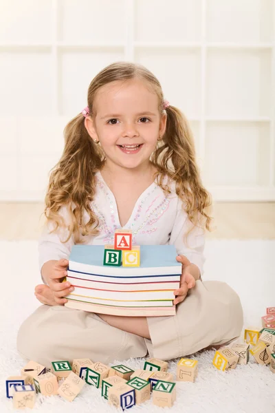 Kitap ve alfabe tahta bloklar ile küçük kız — Stok fotoğraf
