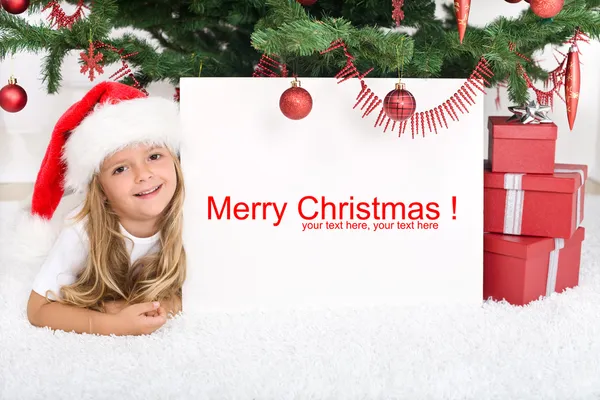 Klein meisje onder de kerstboom met banner — Stockfoto