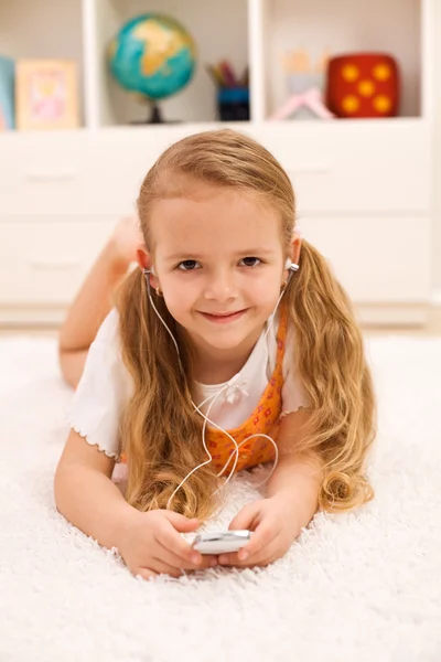 Маленькая девочка слушает портативные музыкальные устройства — стоковое фото