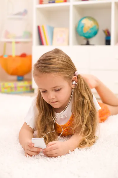 Маленькая девочка слушает музыку, лежащую на полу — стоковое фото
