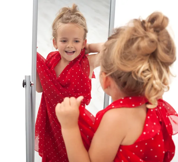 ミラーの前にドレスをしようとしている小さな女の子 — ストック写真