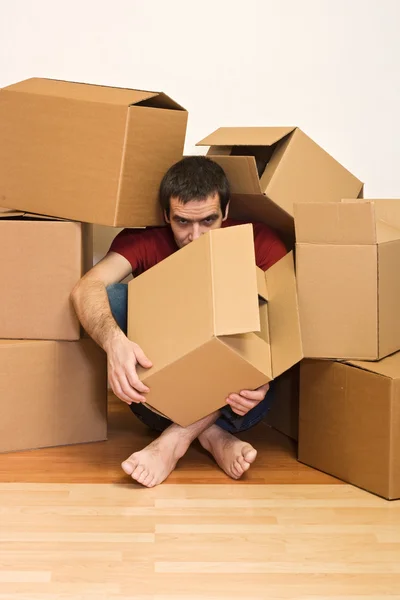 Man under cardboard boxes on the floor - moving concept — Stock Photo, Image