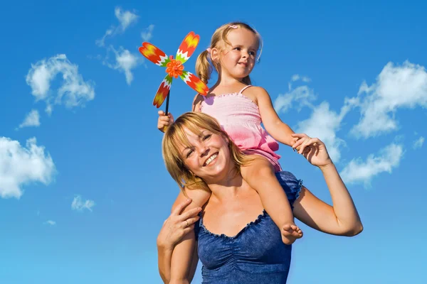 Frau mit kleinem Mädchen gegen den Sommerhimmel — Stockfoto
