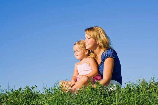 Kvinna och liten flicka sitter utomhus — Stockfoto