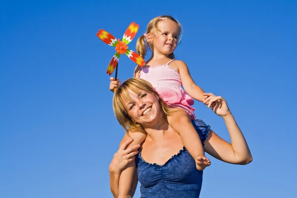 Woman with little girl against summer sky — Stock Photo, Image