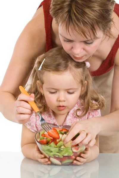 Kvinna och lilla flickan förbereder fruktsallad — Stockfoto