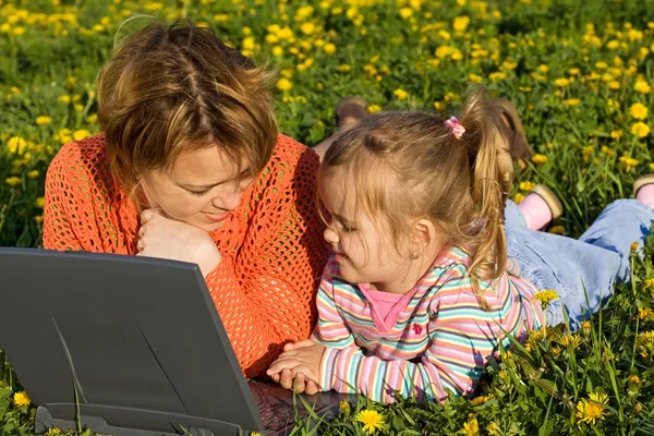 Woman and little girl relaxing on the flower field — Stock Photo, Image