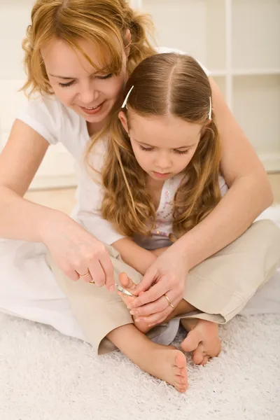 Aliciamento pessoal - mulher e pequena menina cortando unhas do pé — Fotografia de Stock
