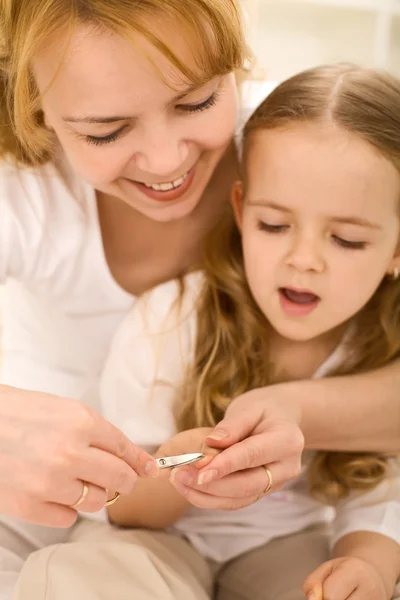 Verzorgen van thema - vrouw snijdt kleine meisjes nagels — Stockfoto