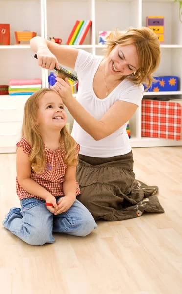 Woman combing little girls hair — Stock Photo, Image
