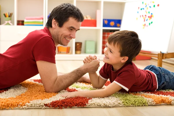 Happy kid and his father arm wrestling — Stock Photo, Image
