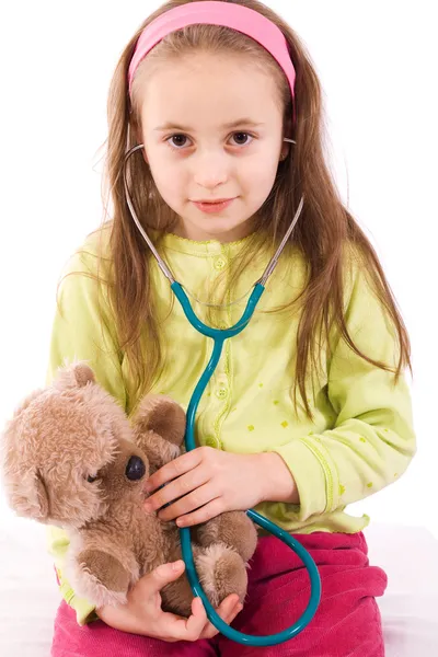 Bedårande liten flicka spelar läkare med en nallebjörn Stockbild