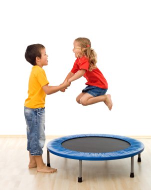 Kids having fun with a trampoline in the gym clipart