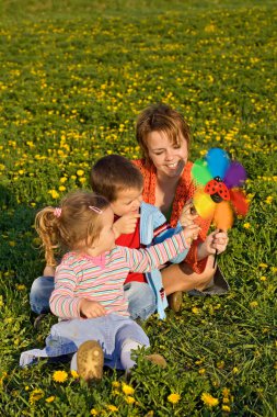 Woman and kids playing with a windmill toy clipart