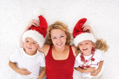 Woman and kids lating on the floor at christmas time clipart