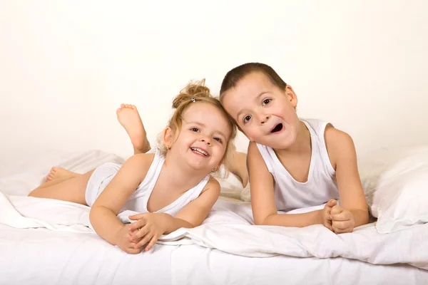 Niños divirtiéndose holgazaneando en la cama — Foto de Stock