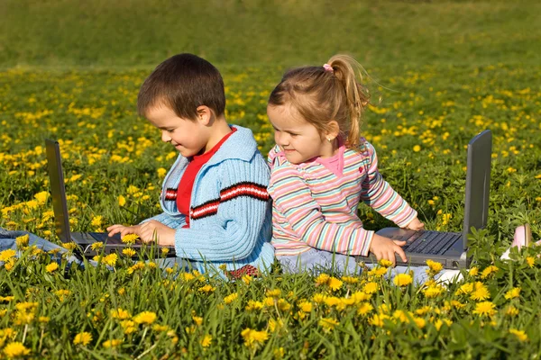 Barn med bärbara datorer på fältet blomma — Stockfoto