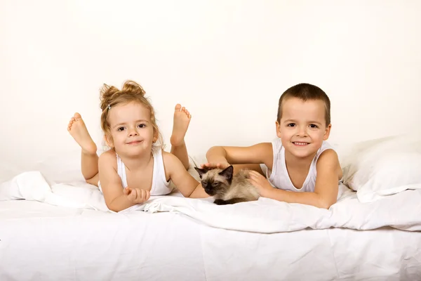 Kinder mit ihrem Kätzchen auf dem Bett — Stockfoto