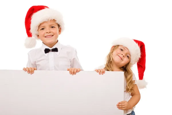 Crianças com chapéus de Papai Noel e banner branco para texto — Fotografia de Stock