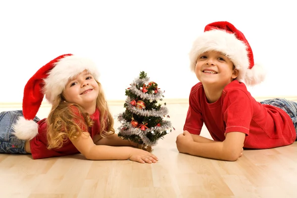 笑容灿烂的孩子在圣诞节的时候躺在地板上 — 图库照片