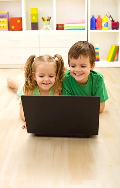 Kids with laptop laying on the floor — Stock Photo, Image