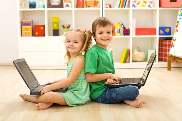 Crianças felizes com laptops sentados no chão — Fotografia de Stock
