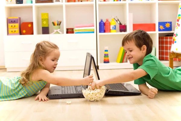 Gyerekek a pattogatott kukoricát eszik laptopok — Stock Fotó