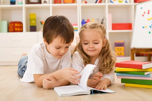 Öğretim ve kız kardeşi nasıl okunacağını gösteren okul çocuğu — Stok fotoğraf