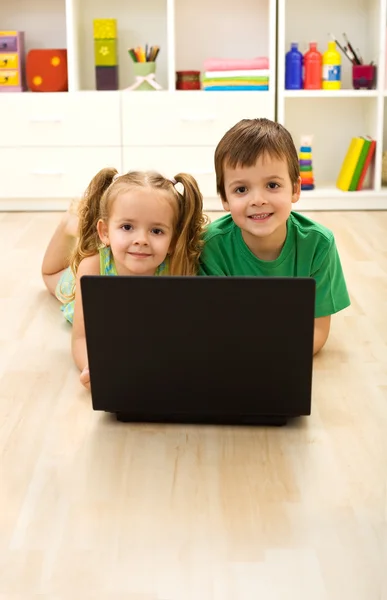 Kids with laptop laying on the floor at home — Stock Photo, Image