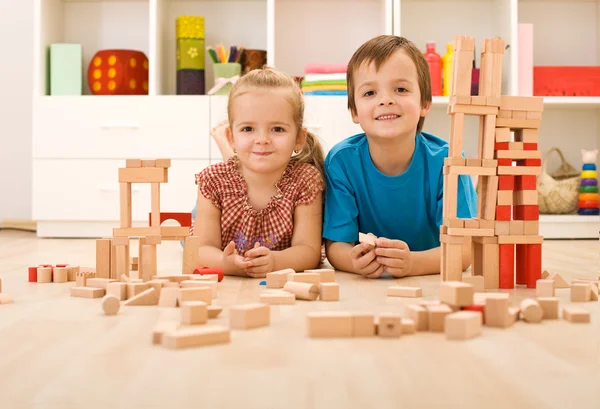 Niños felices con bloques de madera en el suelo — Foto de Stock