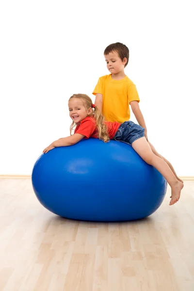 Bambini che fanno esercizi su grande palla di gomma — Foto Stock