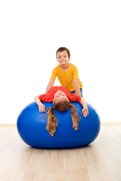 Kids doing streching exercises on large rubber ball — Stock Photo, Image