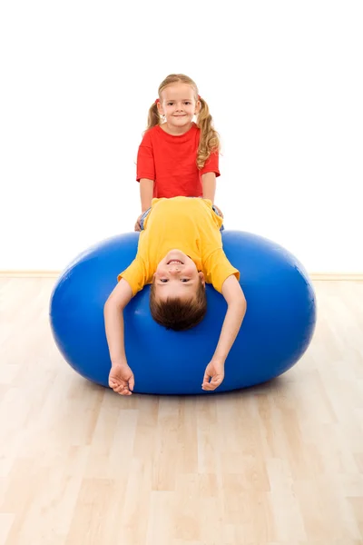 Bambini che fanno esercizi su grande palla di gomma — Foto Stock