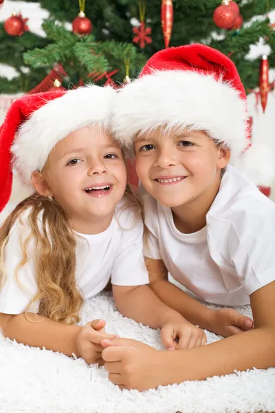 Happy kids in front of christmas tree — Stock Photo, Image