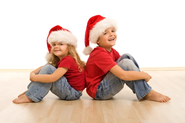 Szczęśliwy kids na podłodze, noszenie Czapki Swiąteczne — Zdjęcie stockowe