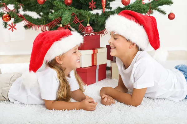 Lachende kinderen tegenover kerstboom — Stockfoto