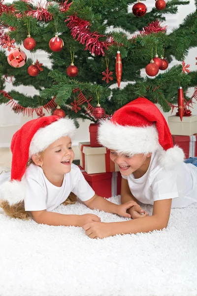 Niños riéndose delante del árbol de navidad — Foto de Stock