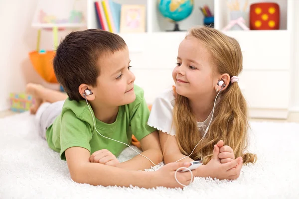 Kids sharing earphones listening to music — Stock Photo, Image