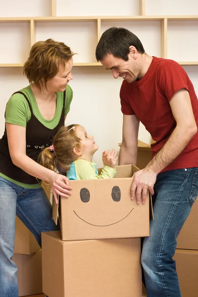 Happy couple with a kid unpacking in a new home — Stock Photo, Image