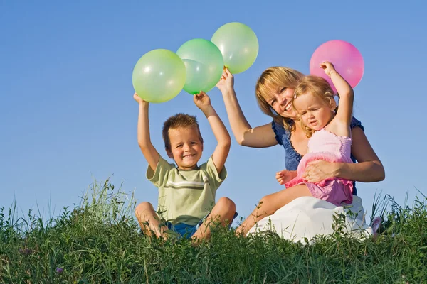 Kids and woman with balloons outdoors — Stock Photo, Image