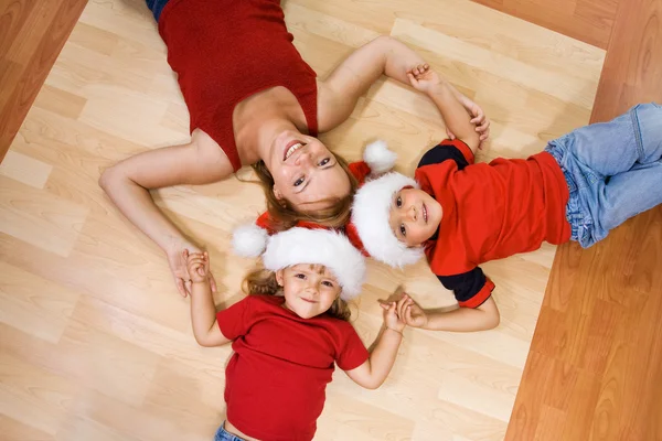 Женщина и ее дети на полу на Рождество — стоковое фото