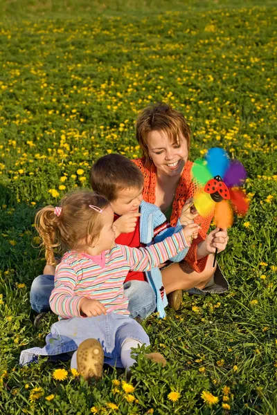 Mulher e crianças brincando com um brinquedo de moinho de vento — Fotografia de Stock