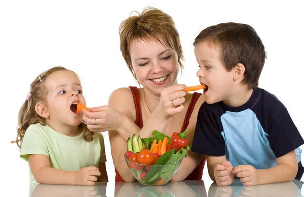 Woman feeding kids with vegetables — Stock Photo, Image